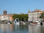 Les quais de la ville d'Agde. On aperçoit le sommet de la Cathédrale Saint-Étienne, l'Hérault et les quais avec quelques bateaux