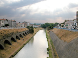 Vue du canal depuis un pont face au soleil et sous un ciel orageux