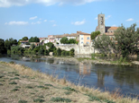 On aperçoit la rivière Aude, de couleur bleue à cette occasion, et sur les berges opposées, quelques maisons de Trèbes et l'église.