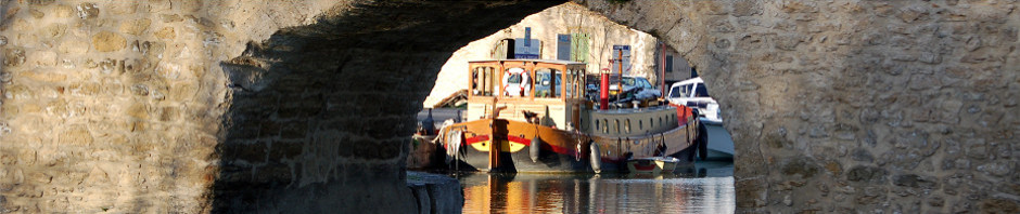 Le Canal du Midi à Capestan. On aperçoit une péniche encadrée par l'arche du pont
