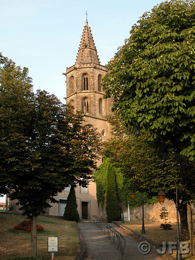 Vue en contre-plongée de l'église d'Avignonet-Lauragais par un beau soir d'été. Le soleil donne à l'ensemble une teinte orangée.