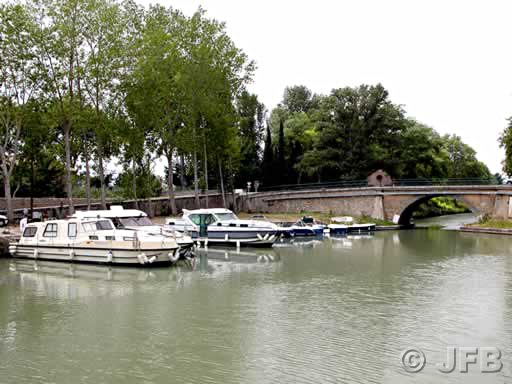 Quelques bateaux amarrés sur le port de Bram. On aperçoit le pont qui laisse passe la route, et en face, les bateaux.