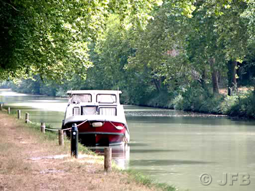 Petite péniche rouge et blanche amarrée non loin du port de Bram