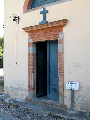 La porte bleue de la Chapelle de Négra, surmontée d'une croix également bleue. A gauche sur le mur et en hauteur, une petite cloche que l'on peut manœuvrer au moyen d'une grande tige de métal. Elle était certainement destinée a appeler les fidèles...