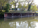 Gros plan sur le vieux lavoir. On distingue bien l'herbe qui recouvre son toit