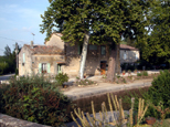 Vue complète de la maison de l'écluse, avec pour premier plan, quelques fleurs et deux platanes