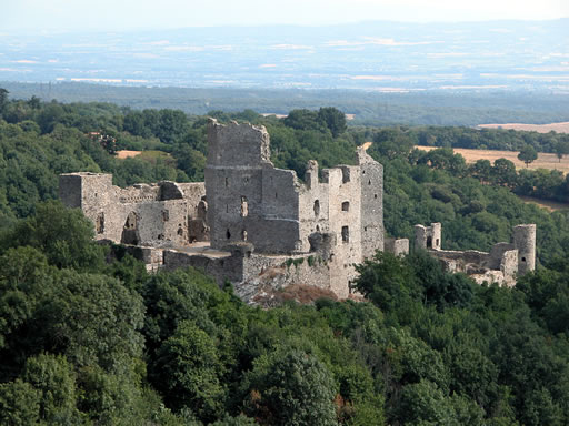 Belle vue d'ensemble du château de Saissac. Il semble émerger de la forêt. Dans le lointain, la plaine de l'Aude et le Seuil de Naurouze