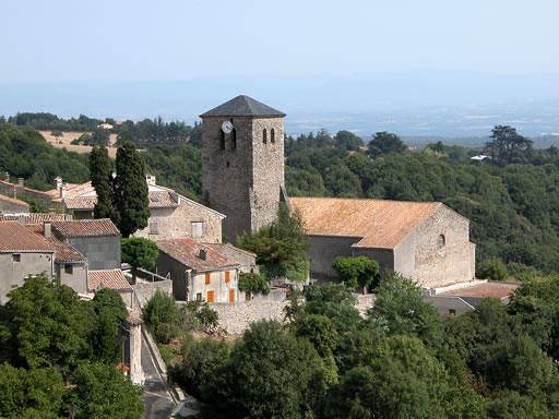 L'église de Saissac par un bel après-midi d'été émerge sur la verdure. Au loin, la plaine bleutée de l'Aude