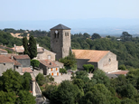 L'église de Saissac par un bel après-midi d'été émerge sur la verdure. Au loin, la plaine bleutée de l'Aude