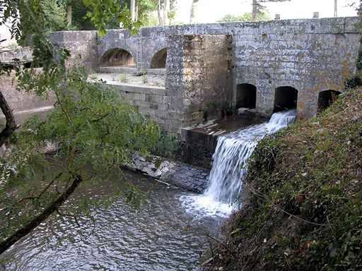 Fonctionnement de l'épanchoir du Laudot, vue d'amont, en contre-jour. L'eau, libérée par une vanne, s'écoule dans le ruisseau du Laudot.