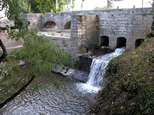 Fonctionnement de l'épanchoir du Laudot, vue d'amont, en contre-jour. L'eau, libérée par une vanne, s'écoule dans le ruisseau du Laudot.