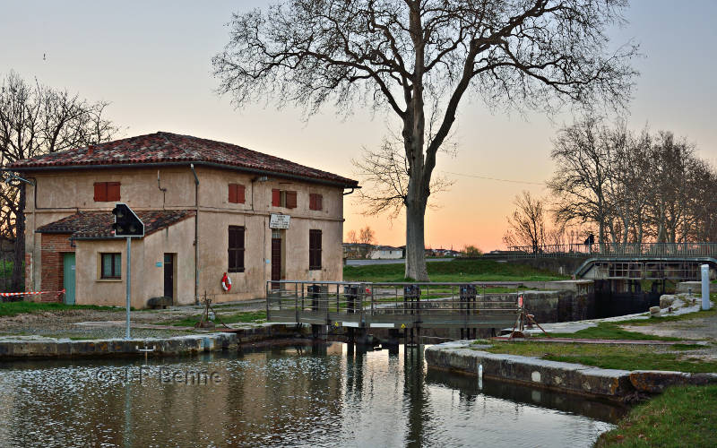 La maison éclusière et le bassin de l'écluse. Au loin, les lueurs du couchant. Les arbres sont encore dépourvus de feuilles.