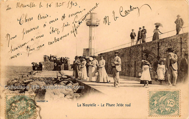 Carte postale ancienne datée du 16 août1903, légendée, la Nouvelle, Le phare jetée Sud. On aperçoit le phare, et quelques groupes de personnes endimanchées.