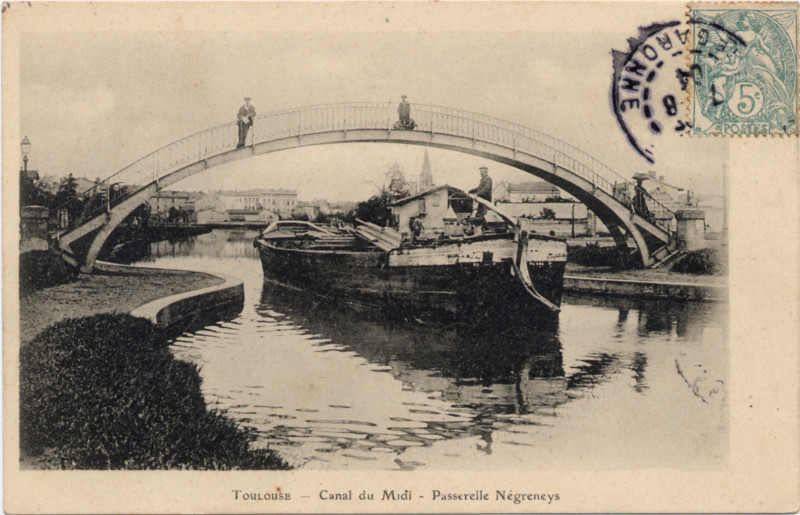 Carte postale ancienne légendée : Toulouse - Canal du Midi - Passerelle Negreneys. Ce n'est pas la carte postale ancienne la plus classique de cet endroit. On aperçoit sur la passerelle, deux individus, l'un nonchalament penché,
    qui observe... et l'autre tout droit ! bien sur, il observe aussi... au dessous d'eux, une péniche passe, et s'éloigne de nous... Elle n'est pas trop chargée car sa ligne de flotaison est très haute sur l'eau. Un marinier dirige la péniche... il s'en va, vers Matabiau, vers Naurouze, vers la Méditerranée...