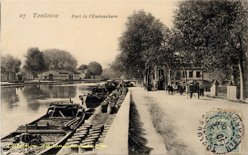 Carte postale ancienne légendée : Toulouse - Port de l'embouchure. À gauche, vue d'ensemble du Port de l'Embouchure.  Trois péniches sont ammarrées rive droite et sur un quai étroit, quelques barriques de vin sont alignées. Un petit muret sépare le quai du chemin, sur lequel on aperçoit deux charettes tirées par des chevaux. À droite également, quelques platanes.