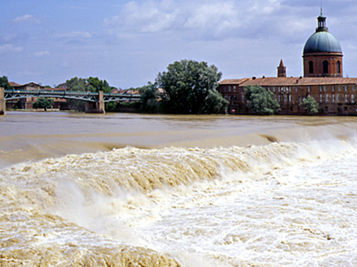 La crue est telle que la différence de niveau entre le haut et le bas de la chaussée est réduite de moitié. La Garonne se comporte comme un torrent boueux, et l'eau forme de violents remous. Sur l'autre rive, on aperçoit le dôme de la Grave